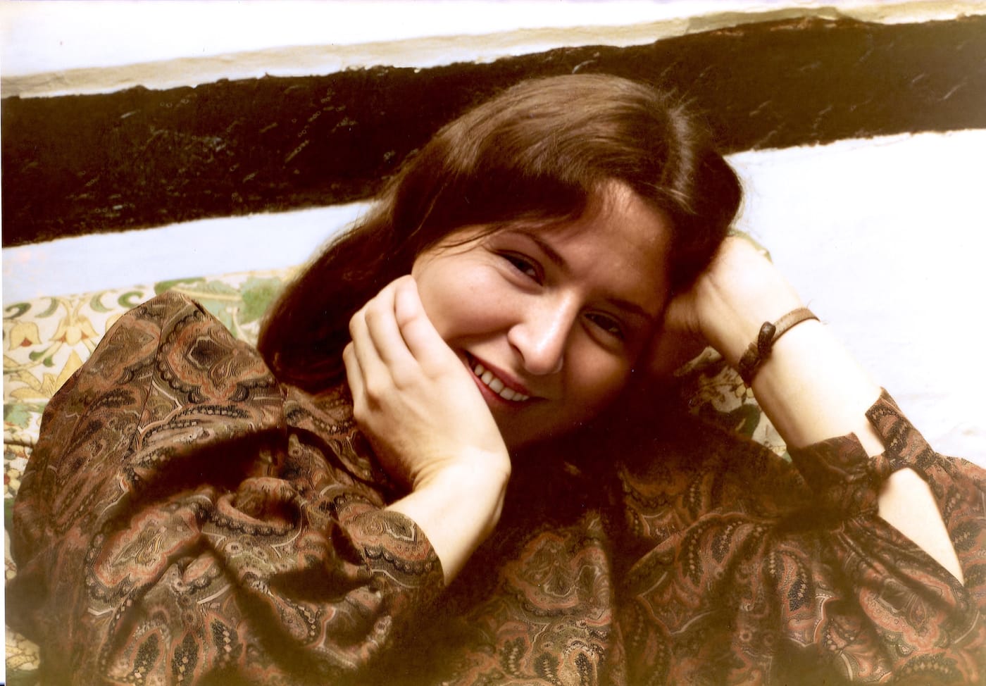 A young woman in a paisley blouse resting her cheek on her hand, photographed in the 1970s