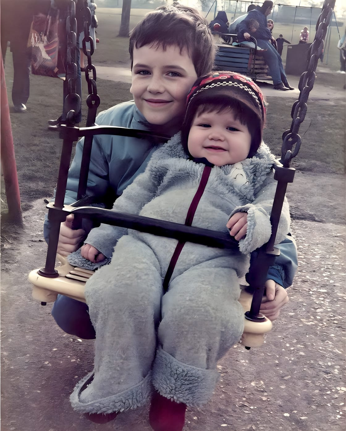 Two young children on a playground swing, photographed in the 1980s